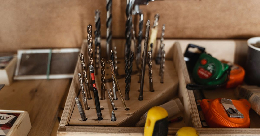 A collection of professional nail drill bits in various shapes and grits arranged on a white background, illustrating how to choose nail drill bits for home manicures.