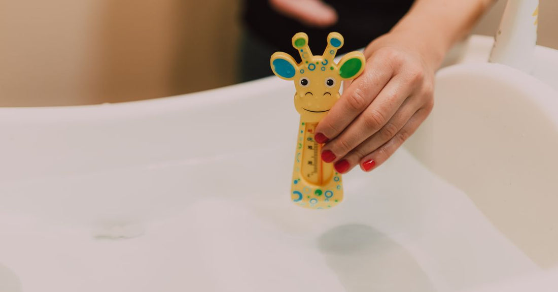 A newborn baby safely supported in a baby bath basin with gentle baby skincare products nearby, demonstrating how to bathe a newborn safely.
