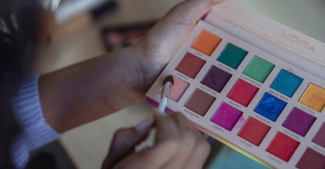 Flatlay of professional makeup palettes with eyeshadows and brushes on a white marble surface, showing where to buy makeup palettes online in the UK.