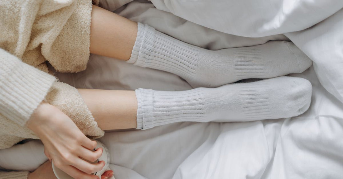 White cotton moisturizing socks laid flat on a marble surface, demonstrating breathable fabric for dry feet overnight care.