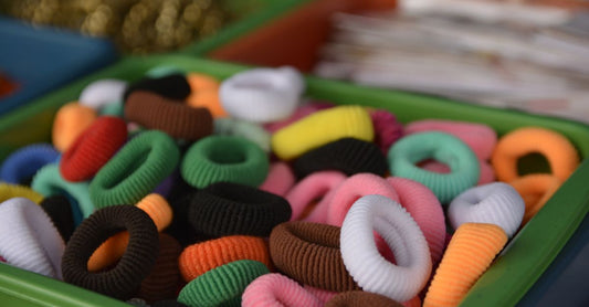 A flat lay of colourful hair elastics and ties on a white background, illustrating how to choose elastics and ties UK
