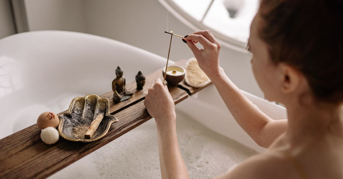 A wooden bath caddy holding a book, a candle, and a rolled towel, illustrating a bath & bathing accessories buying guide.