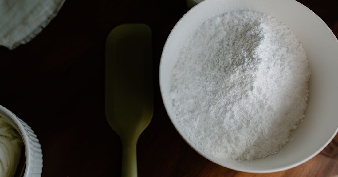 A white bowl of professional hair bleach powder next to a tint brush, showing how to choose bleaching products for at-home use.