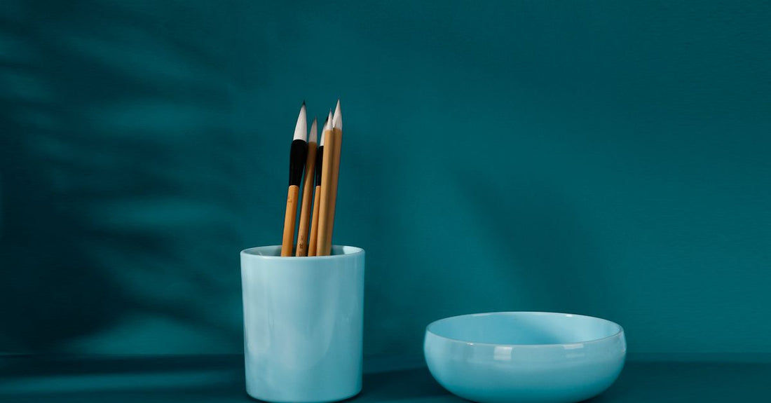 How to clean makeup brushes properly: close-up of synthetic brushes swirled in a cleansing bowl with gentle soapy water.