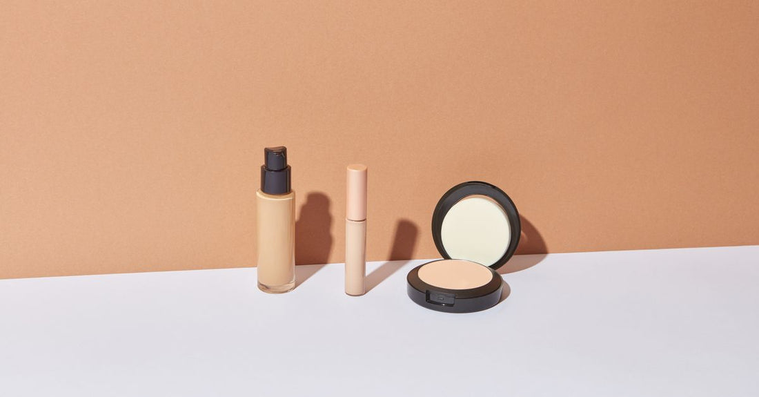 Flatlay of foundation bottles and makeup brushes on a white surface, foundation buying guide UK