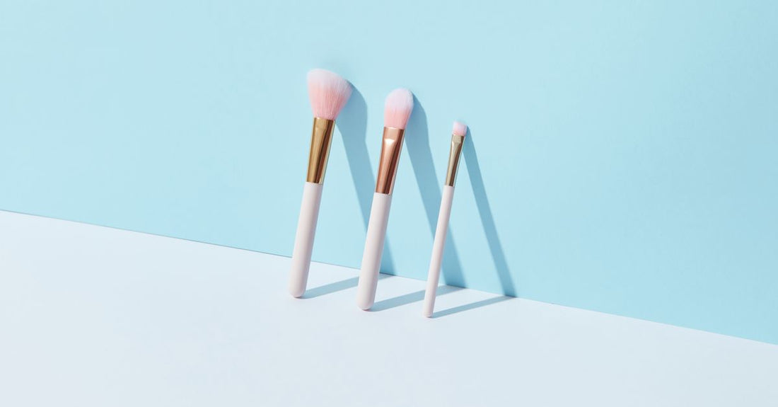 A selection of face brushes including a foundation brush, powder brush, and silicone cleansing brush, laid flat on a white surface.