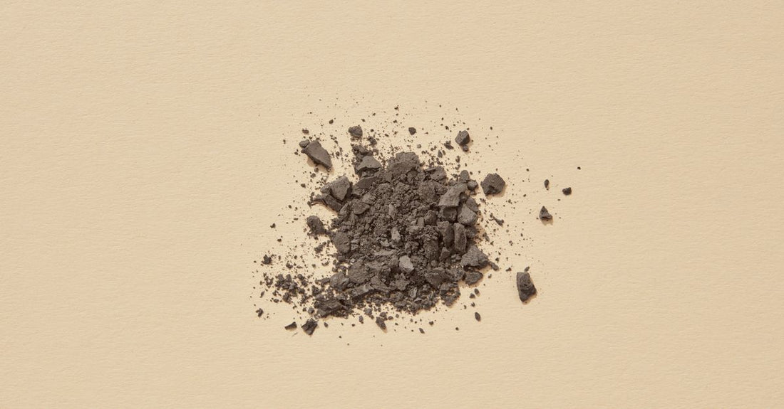 A jar of loose translucent setting powder with a velour puff on a marble surface, illustrating a powder buying guide UK for beginners.