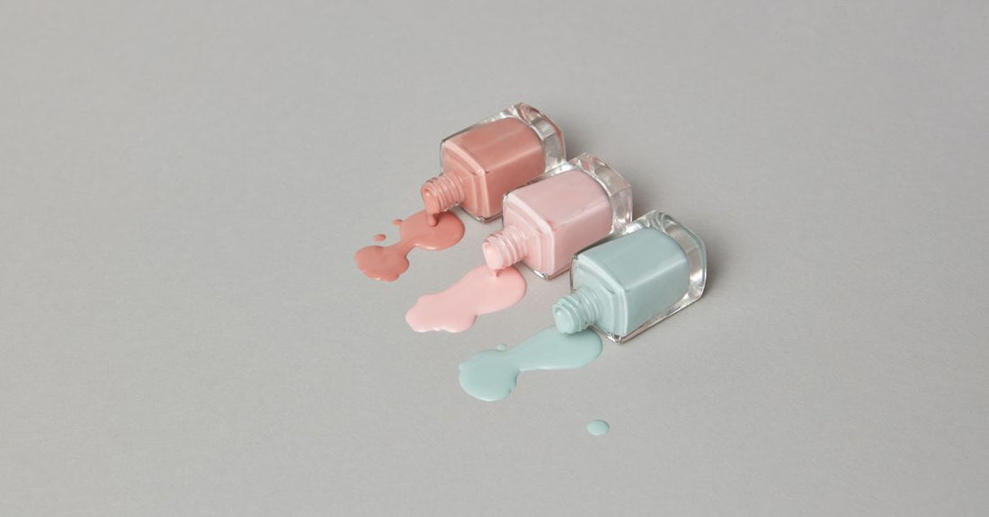Two clear nail polish bottles labelled base coat and top coat on a neutral background, illustrating a combination base and top coats buying guide.