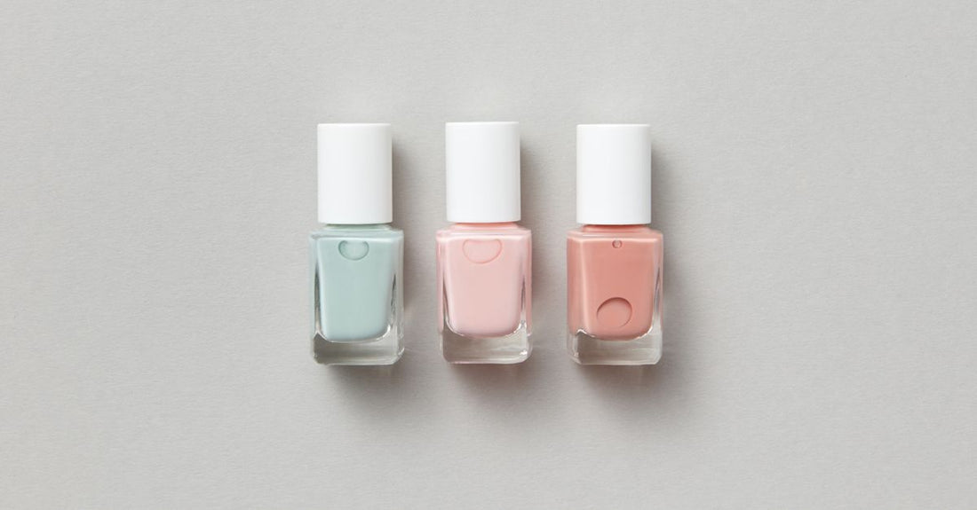 Collection of nail polish bottles and cotton pads on a white surface, demonstrating how to remove nail polish without remover using alternative methods.