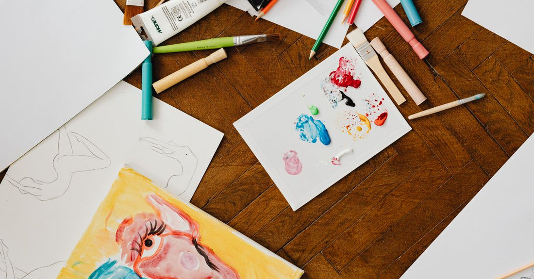 A flatlay of vibrant, professional-grade body paint palettes and brushes on a clean white surface, showcasing the best body paint 2026 options.