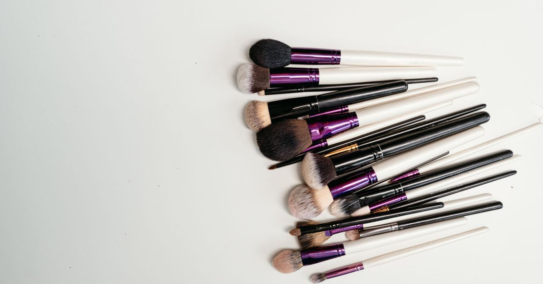 A flatlay of various blush brushes on a marble surface, showing different shapes and bristle densities for how to choose blush brushes