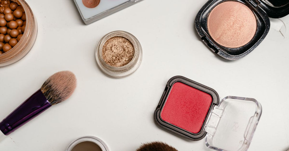 A flatlay of assorted blush compacts, cream sticks and powder pans on a white marble background, illustrating a blush buying guide.