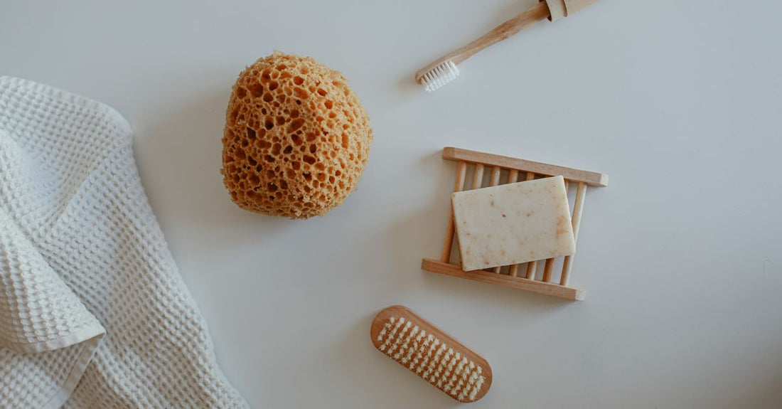 Natural sea sponge and wooden back brush on a bathroom shelf, illustrating how to choose bathing accessories UK