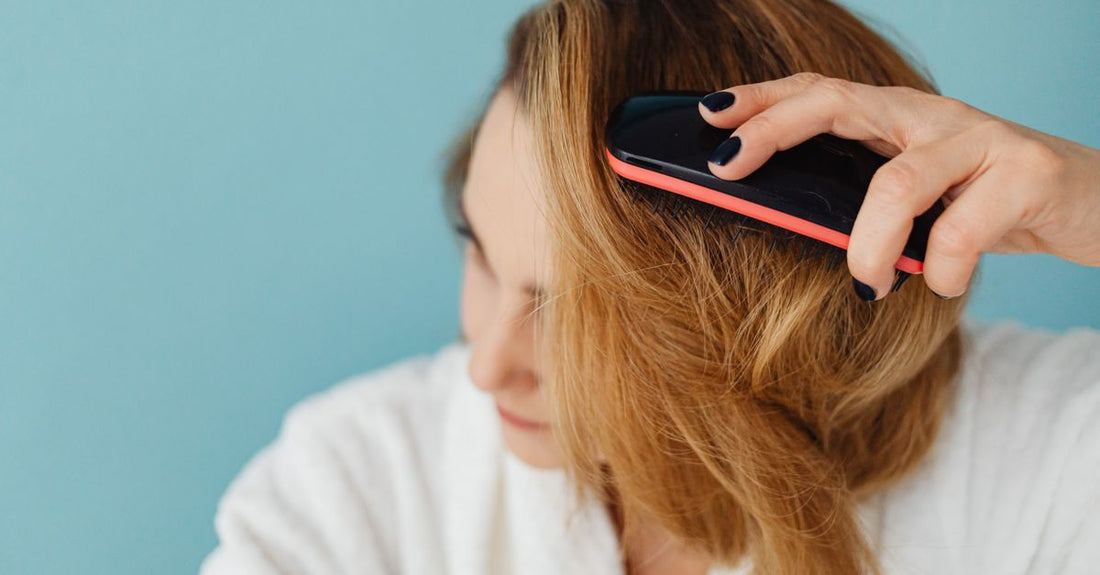 A sleek ceramic hair straightening brush resting on a white marble surface, demonstrating how to straighten hair without heat damage using modern tools.
