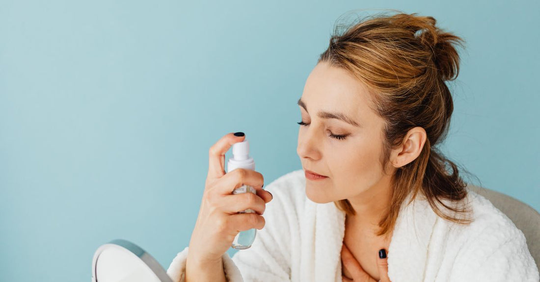 Makeup finishing spray bottle with fine mist over a dressing table