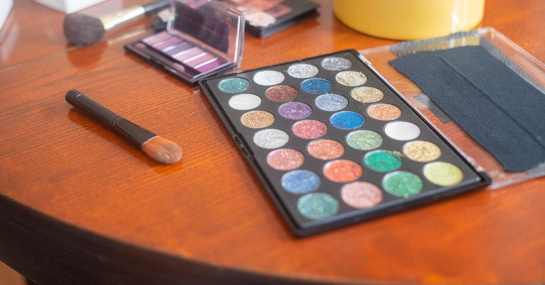 A flat lay of various neutral eyeshadow palettes, brushes, and swatches on a clean white background, illustrating an eyeshadow buying guide.