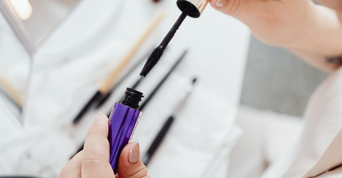 A sleek black mascara tube on a white marble surface, illustrating how to choose mascara UK for your daily routine.