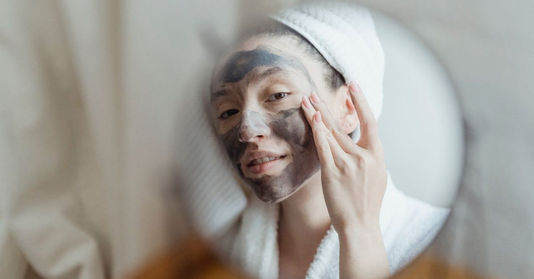 Four face mask products on a white surface: a pink clay mask tub, sheet mask packets, a sleeping mask jar, and a hydrogel mask.