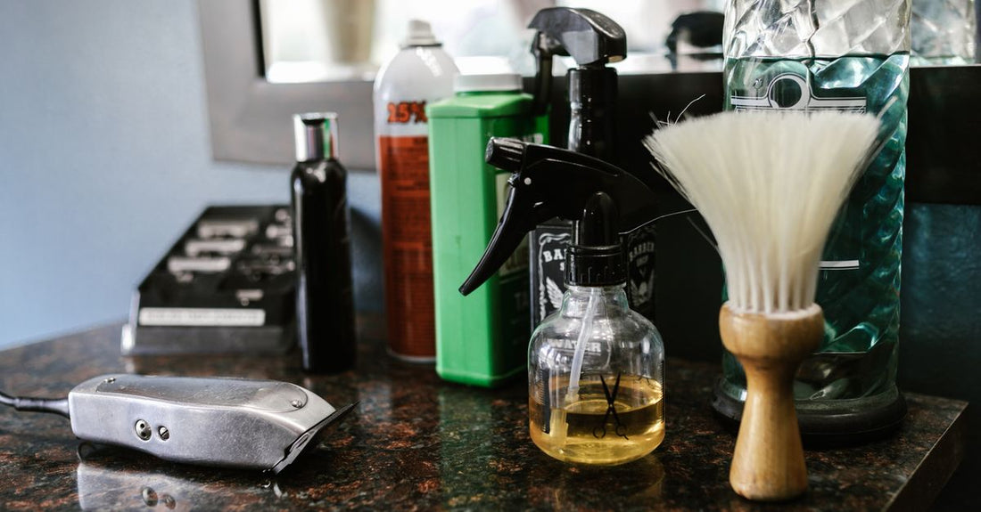 A wooden beard brush and a bottle of beard oil resting on a textured surface, illustrating how to train beard to grow downwards.