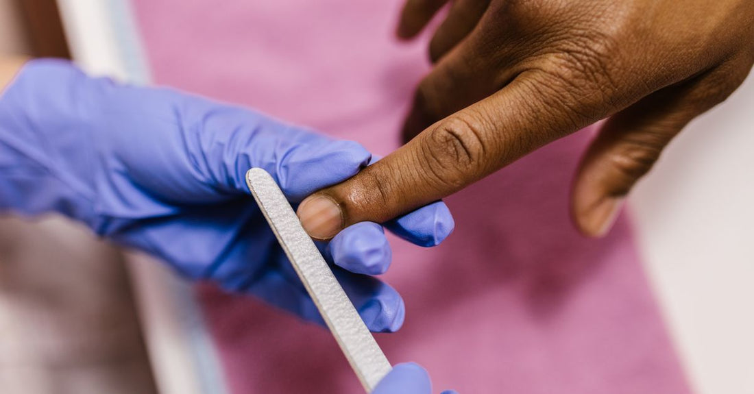 A stainless steel and a glass cuticle pusher lying on a white marble surface, illustrating a cuticle pushers buying guide.