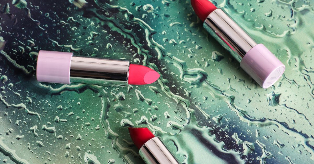 A flatlay of lip care products including balms, scrubs, and oils on a marble surface, illustrating a lip care buying guide for summer.
