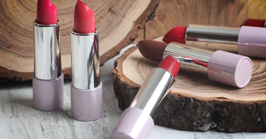 A flatlay photograph of various lipstick tubes in neutral, red, and pink shades on a white marble surface, illustrating how to choose lipstick shades.
