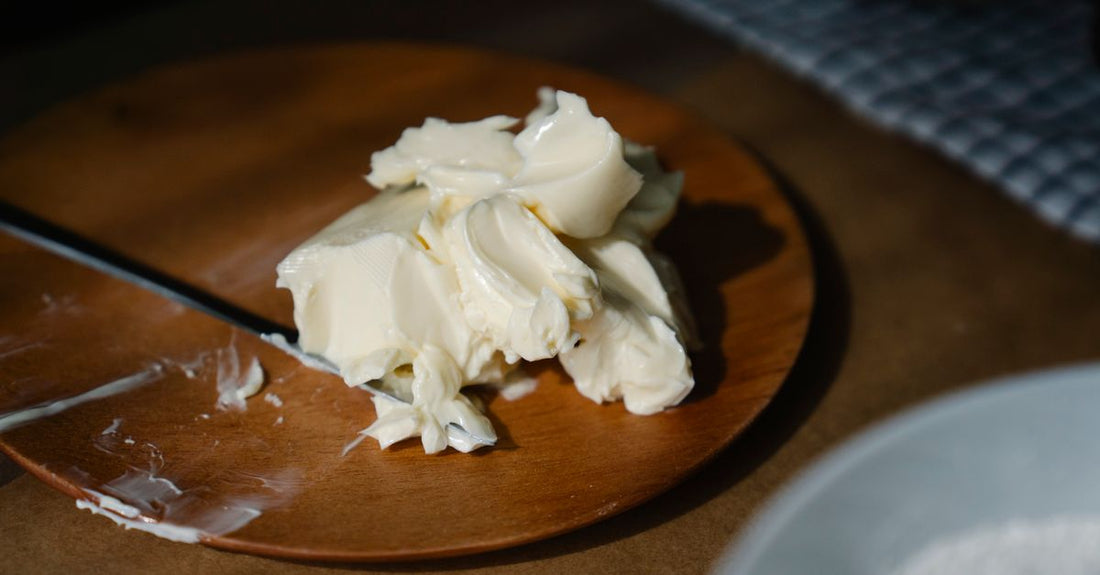 A jar of pure shea body butter on a flat surface, illustrating how to choose body butters with rich texture.