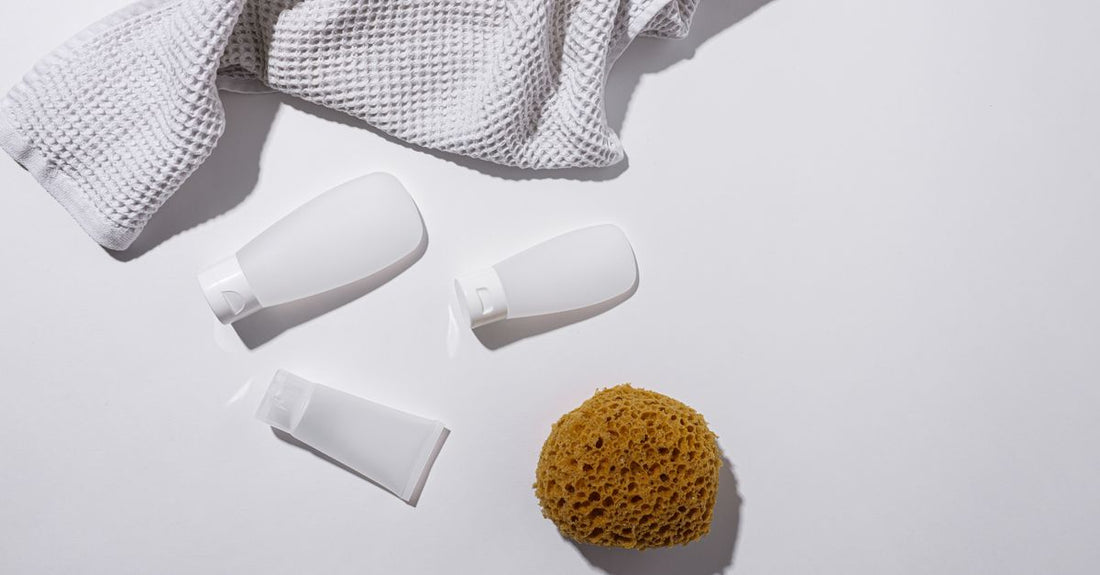 A flatlay of five different colour-safe shampoo bottles on a white marble surface, representing the best shampoo for coloured hair UK options.