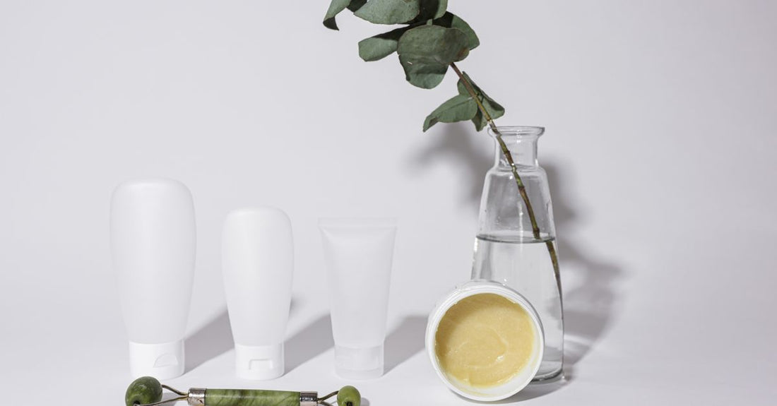 Assorted moisturisers and balms in glass jars arranged neatly on a light marble surface, illustrating how to choose balms & moisturisers for different skin types.