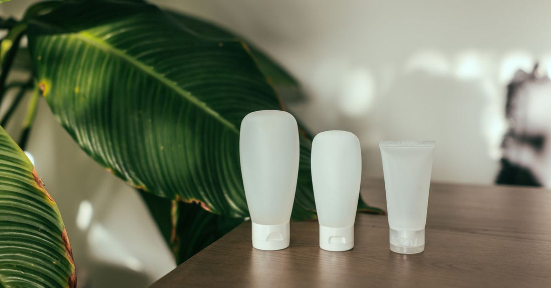 A flat lay of sleek body self-tanner bottles and a soft mitt on a marble surface, representing the best body self-tanners 2026 for a natural, streak-free UK glow.