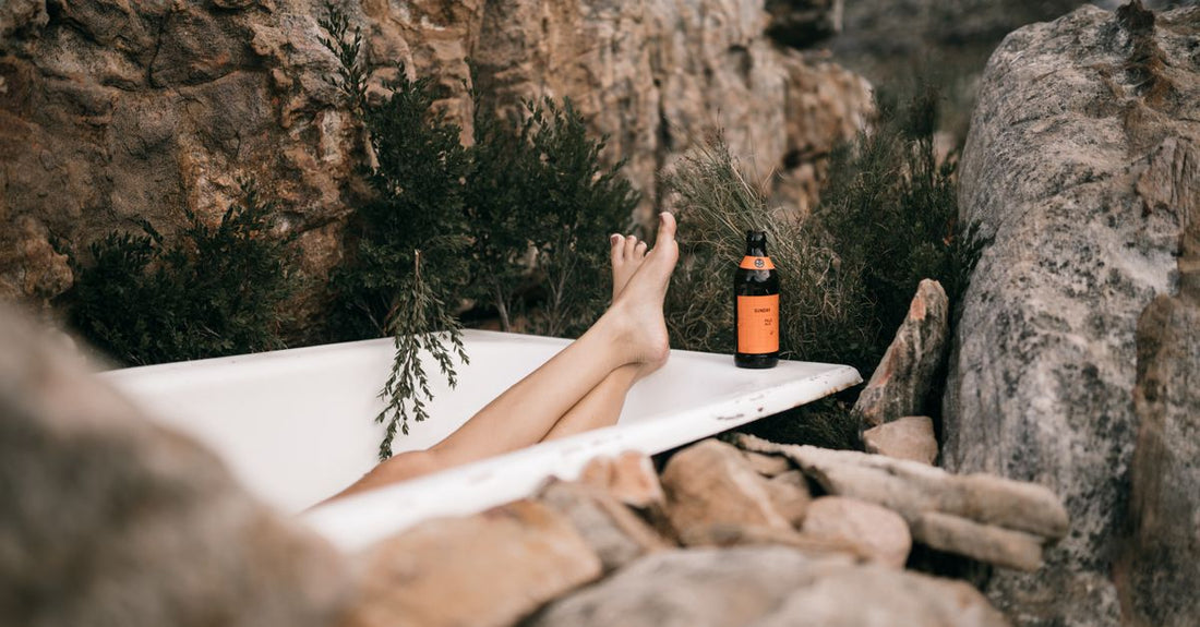 A bottle of self-tan mousse next to a tanning mitt on a white surface, illustrating a body self-tanners buying guide