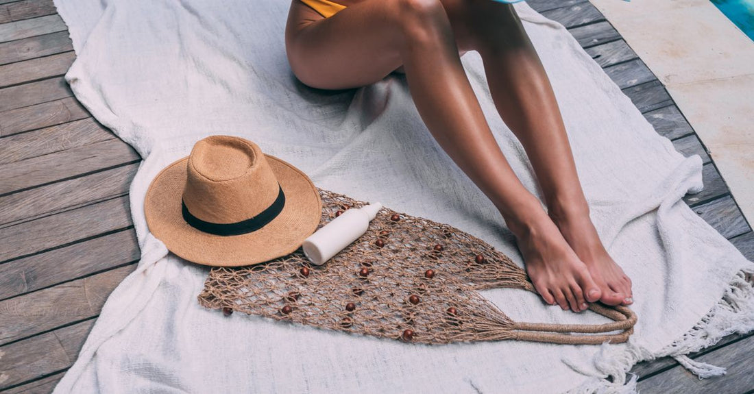 A selection of body sunscreens arranged on a bright beach towel, representing a body sunscreens buying guide for UK summer.