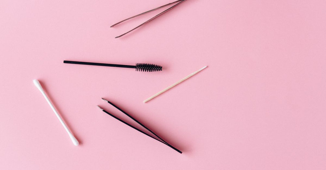A flatlay arrangement of eyebrow pencils, powders, and gels in neutral brown shades, illustrating how to choose eyebrow colour.