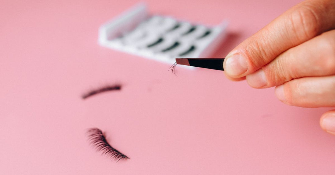 A close-up of a white eyelash glue bottle with a fine-tip applicator, representing the best eyelash glue for sensitive eyes UK, on a clean beauty table.
