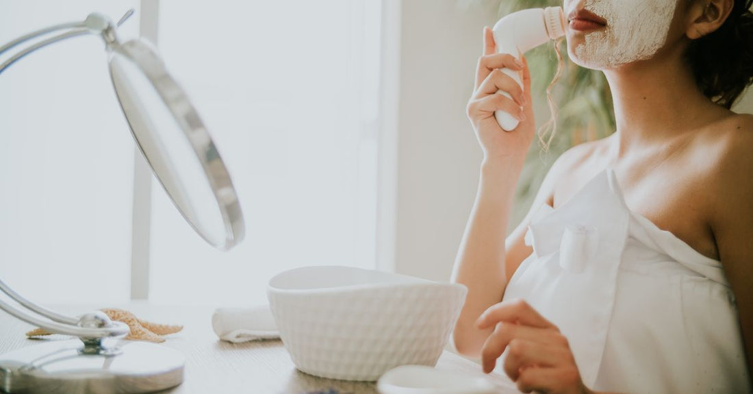 A wooden-handled manual facial cleansing brush resting on a clean bathroom shelf, perfect for finding where to buy manual facial cleansing brushes online in the UK.