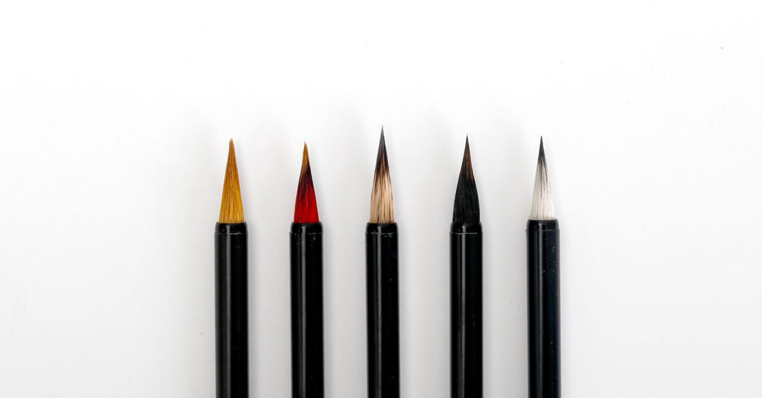 A flatlay of pink nail art brushes, dotting pens, and a palette on a white desk, representing where to buy nail art brushes online in the UK.