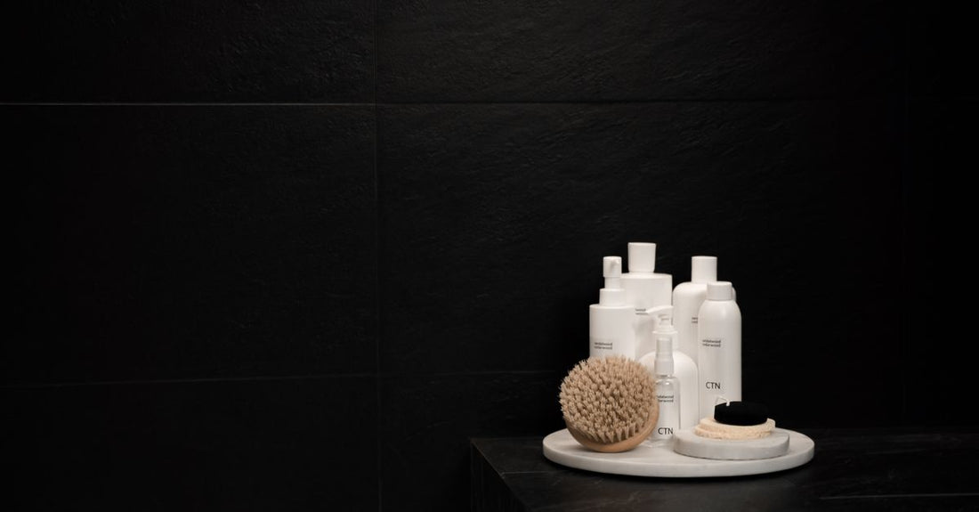 A bottle of curly hair conditioner on a bathroom shelf next to a curl defining cream jar, illustrating how to condition curly hair for definition.