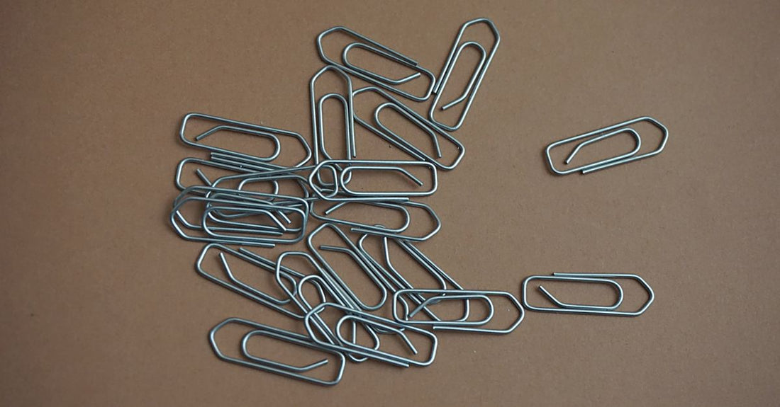 An assortment of colourful metal snap hair clips and duckbill styling clips laid flat on a neutral surface, illustrating a clips buying guide for UK shoppers.