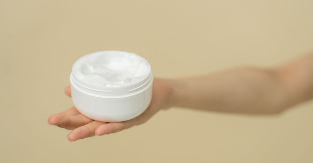 A jar of the best foot cream for cracked heels UK, rich urea formula, on a white surface with green botanical accents.