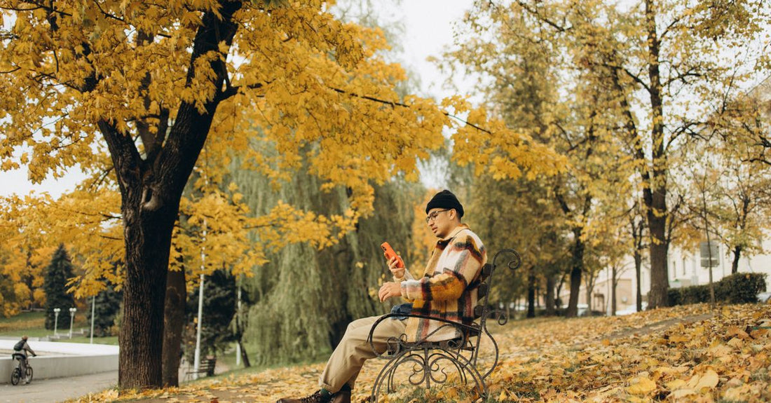 A bottle of styling mousse on a wooden surface with autumn leaves, illustrating how to choose mousses for seasonal hair care.